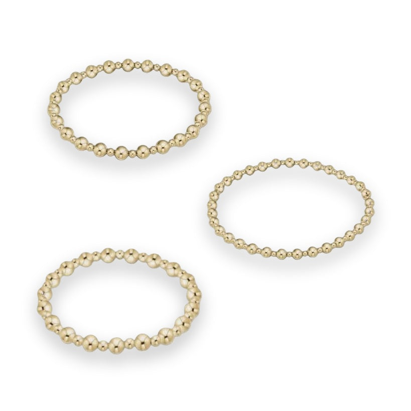 Jewelry product photography of three gold beaded bracelets on a neutral studio background featuring polished spherical beads of varying sizes with high-shine reflective surfaces