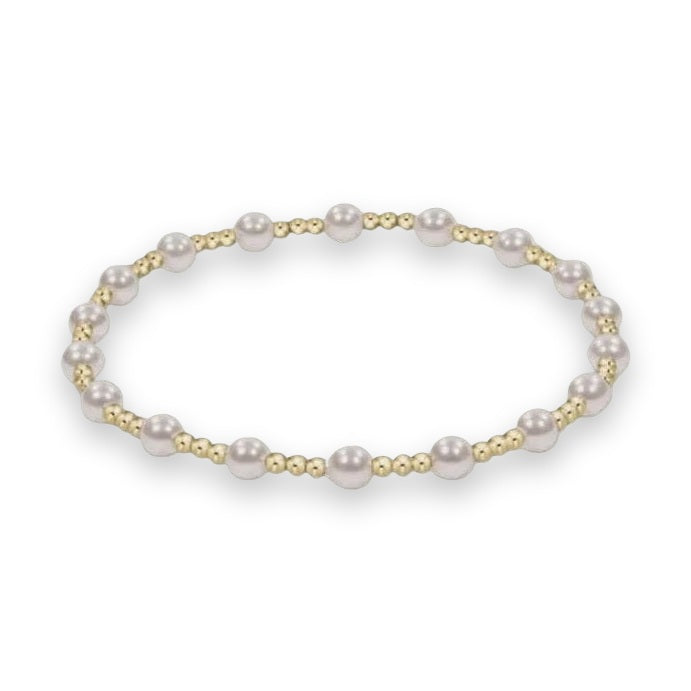 Beaded jewelry bracelet featuring alternating iridescent white pearls and clusters of three small polished gold-tone beads on a plain white background