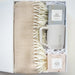 Gift set with beige blanket, mug, and hot cocoa mix in a box on a light background