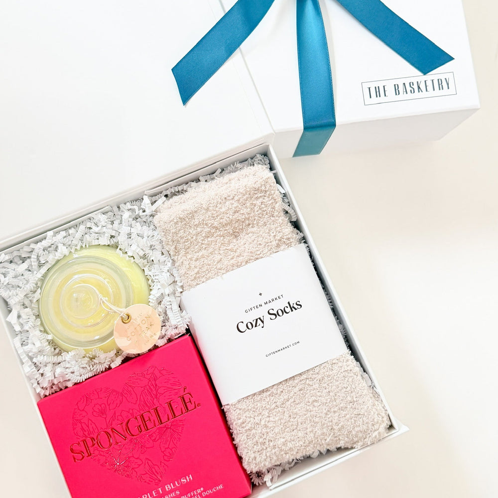 Gift set with socks, soap, and a card in a box with a blue ribbon on a white background