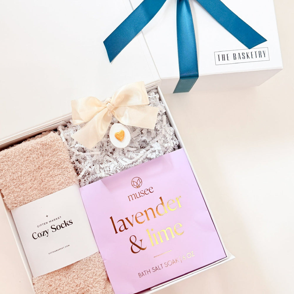 Gift set with socks, bath salts, and a blue ribbon on a white background