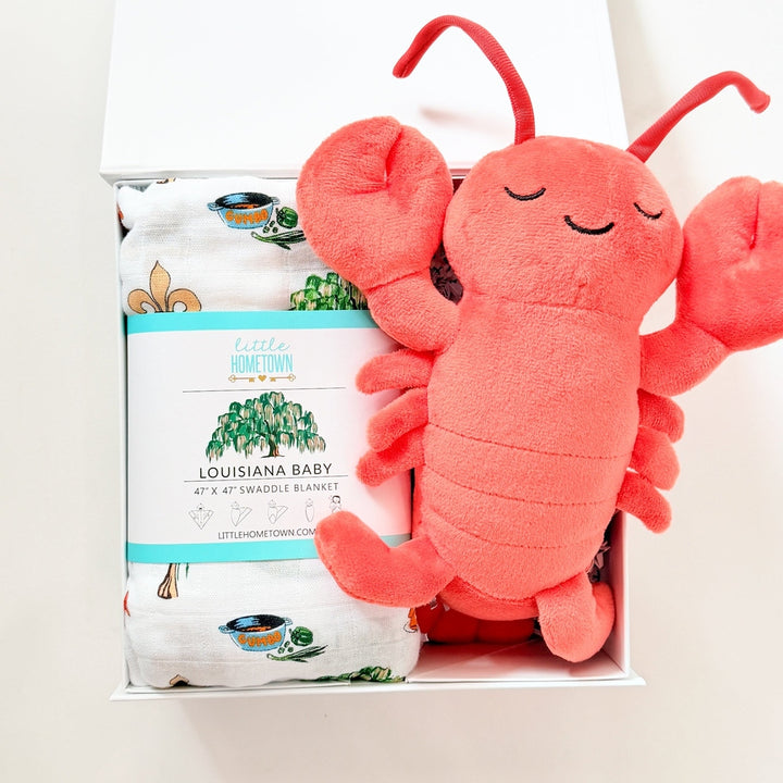 Plush lobster toy in front of a box with a brand logo on a white background