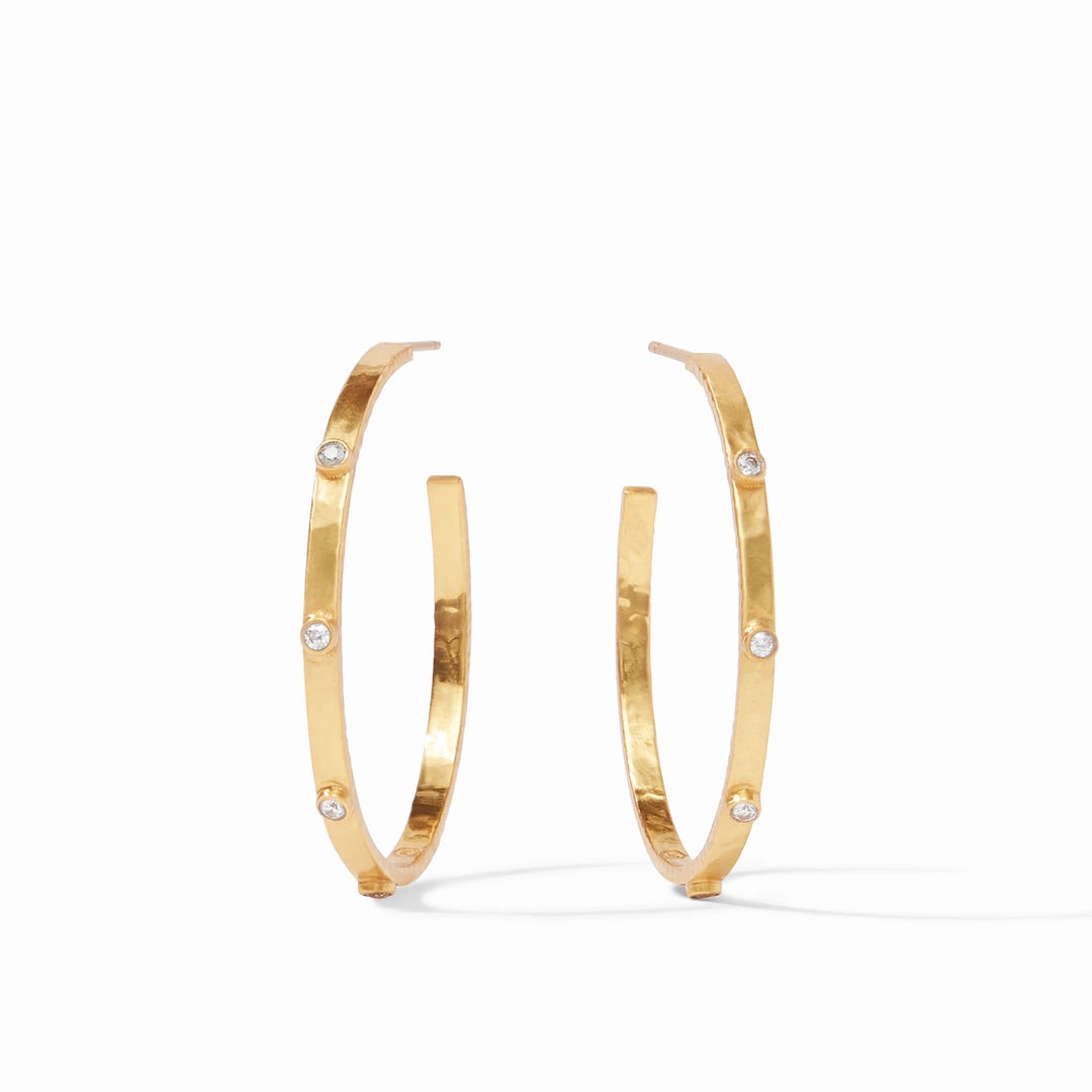 Hammered gold jewelry by Julie Vos featuring a pair of textured open hoop earrings accented with three sparkling bezel-set clear stones on a minimalist white background
