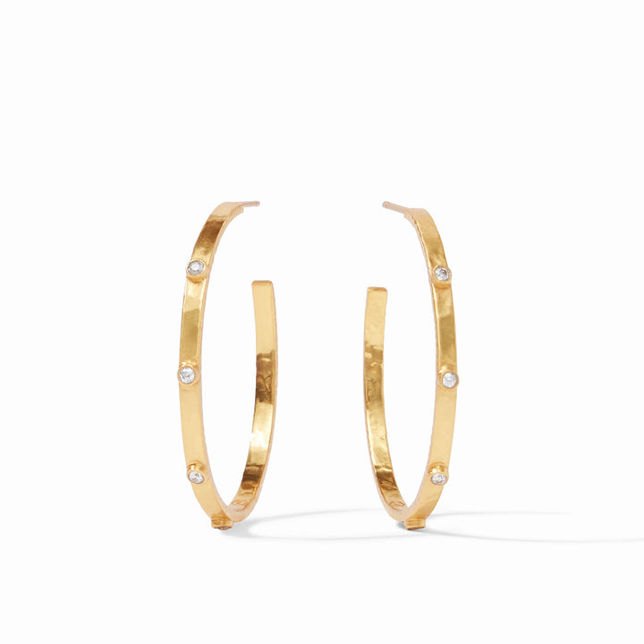 Hammered gold jewelry by Julie Vos featuring a pair of textured open hoop earrings accented with three sparkling bezel-set clear stones on a minimalist white background