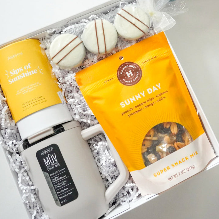 Gift box with coffee mug, snacks, and a bottle of water on a white background