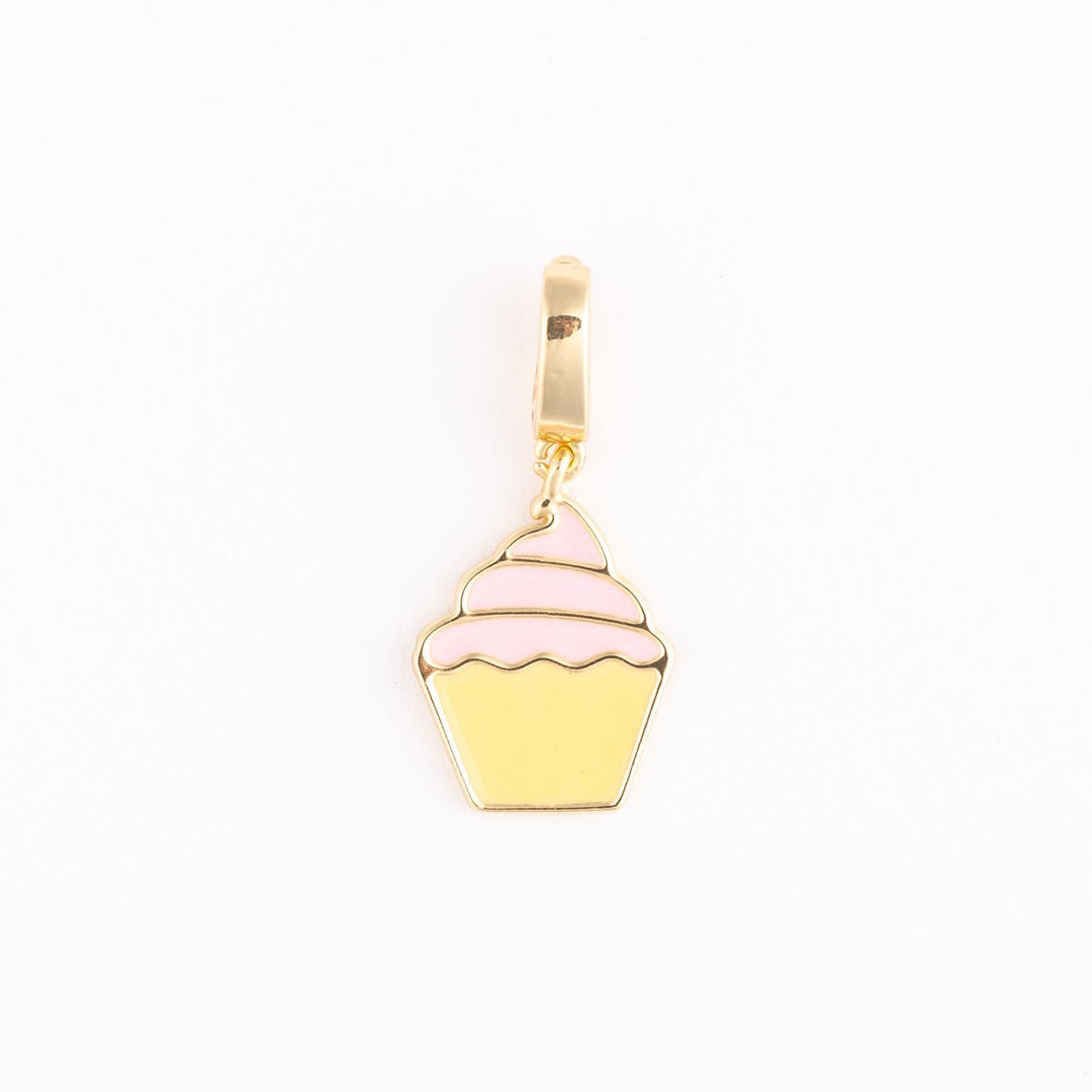 Enamel and gold-tone metal jewelry charm of a cupcake centered on a plain white background featuring tiered pink enamel frosting, a pale yellow fluted base, and a polished gold hanging loop