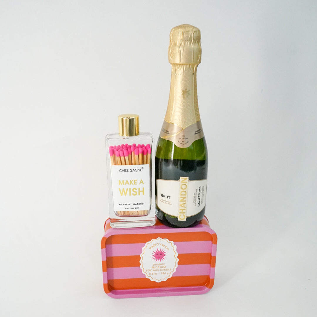 Bottle of champagne and a bottle of matches on a striped stand against a white background