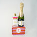 Bottle of champagne and a bottle of matches on a striped stand against a white background
