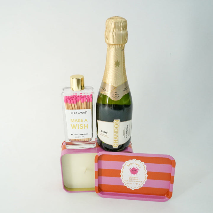 Bottle of champagne, matches, and a striped box on a white background
