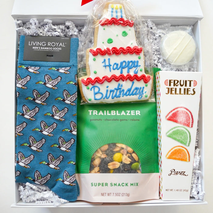 Gift box with birthday-themed items including socks, snack mix, and a cake-shaped cookie.