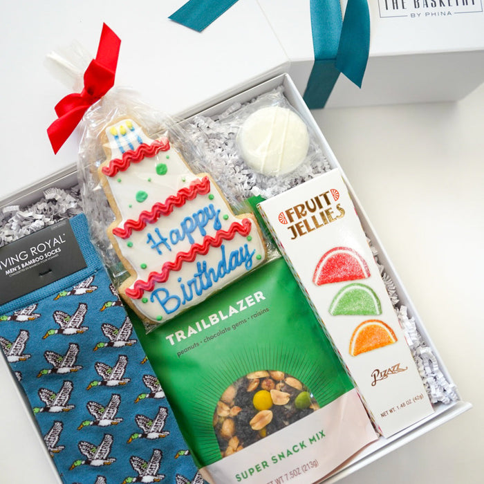 Gift box with cookies, snacks, and a sock, tied with ribbons, on a white background.