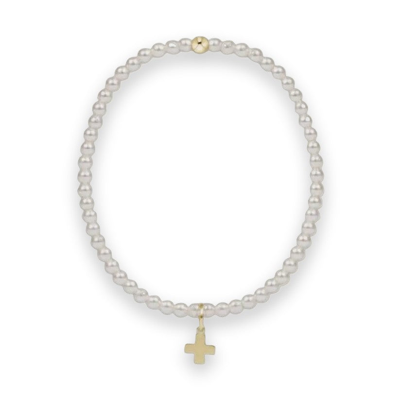 Pearl and gold jewelry featuring a circular strand of lustrous white pearls centered against a light gray background with a polished gold cross charm at the bottom and a single gold bead accent at the top