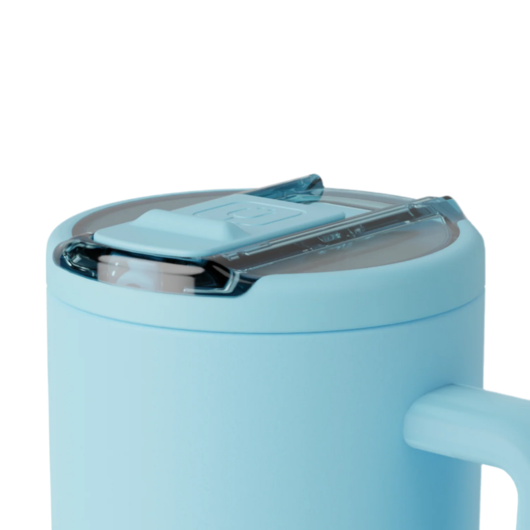 Product photograph of a light blue insulated travel mug on a white background featuring a transparent sliding lid and a smooth matte finish