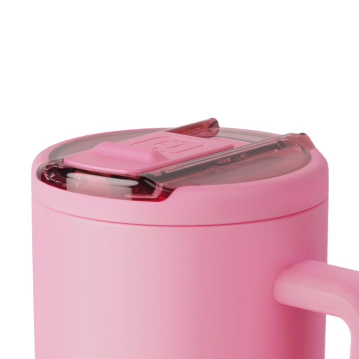 Digital product photograph of a matte pink travel mug featuring a transparent lid with a matching pink sliding closure and a partial view of an ergonomic handle against a white background