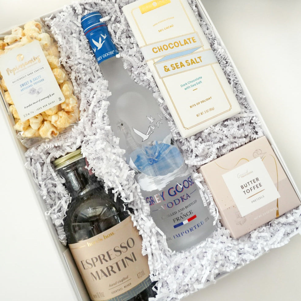 Gift set with a bottle, snacks, and other items in a decorative box on a white background