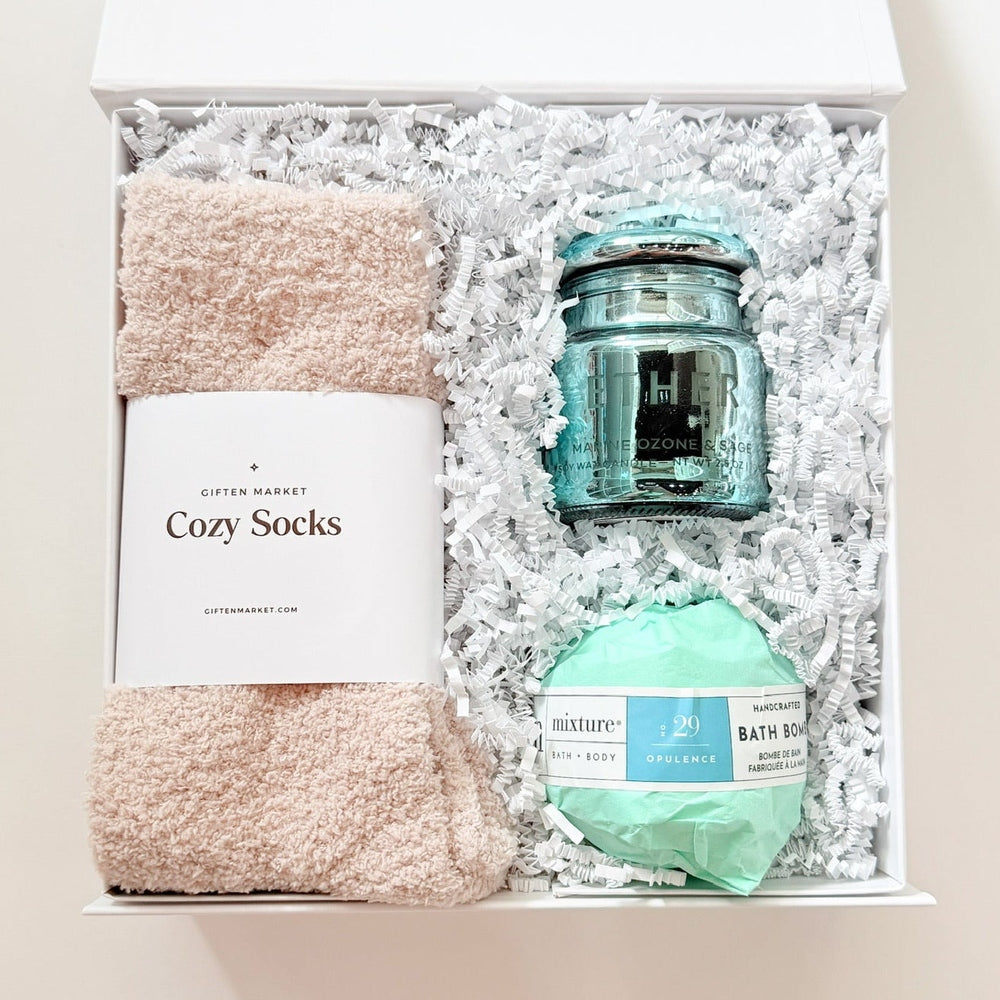 Gift set with socks, candle, and bath bomb in a box on a white background