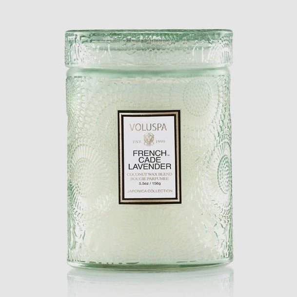 Product photograph by Voluspa of a French Cade Lavender candle from the Japonica Collection against a neutral background, showcasing the intricately embossed pale green glass jar, matching patterned lid, and gold-trimmed white label