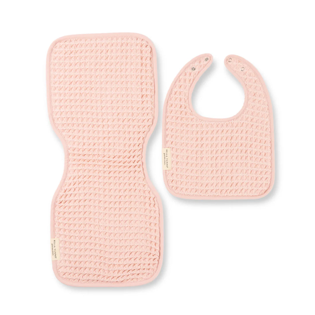 Waffle-weave cotton accessories by Bella Tunno featuring a pink baby bib and contoured burp cloth on a white background with a textured honeycomb pattern and silver snap closures