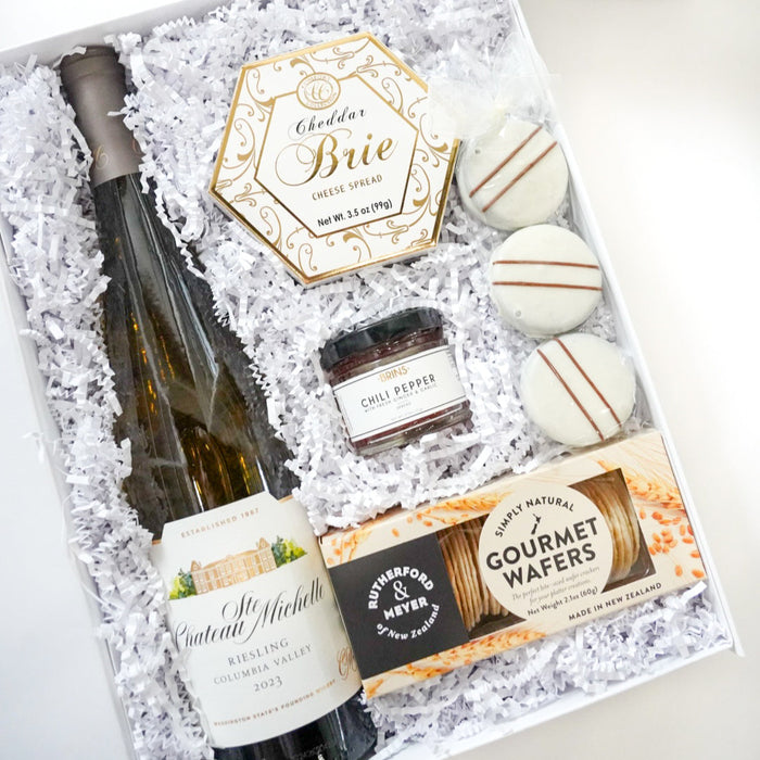Gift set with wine, chocolates, and cookies in a decorative box.