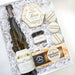 Gift set with wine, chocolates, and cookies in a decorative box.