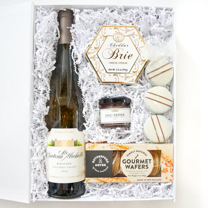 Gift set with a bottle of wine, cheese, and other items in a decorative box.