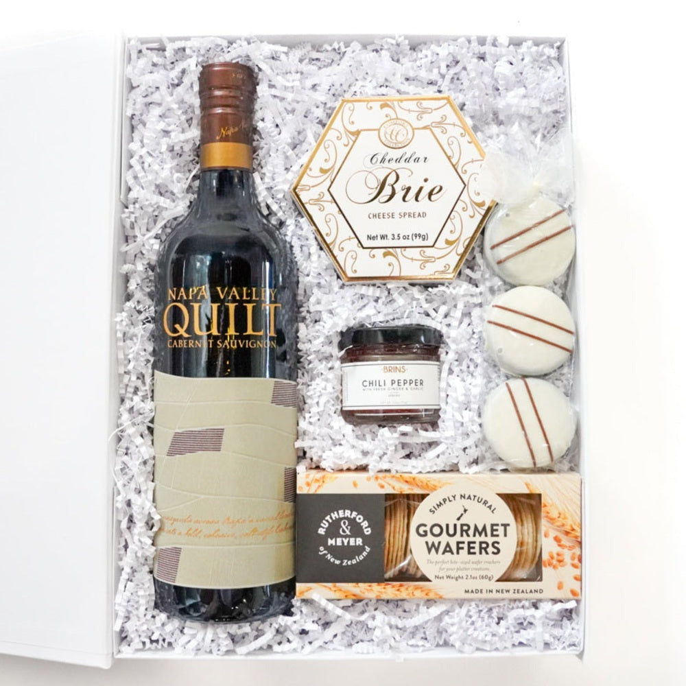 Wine bottle with a box of chocolates and treats on a white background