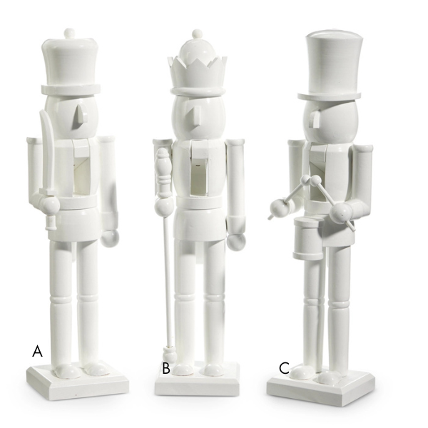 Wooden sculptures of three traditional unpainted white nutcrackers featuring a soldier with a sword a king with a scepter and a drummer with a top hat on a white studio background