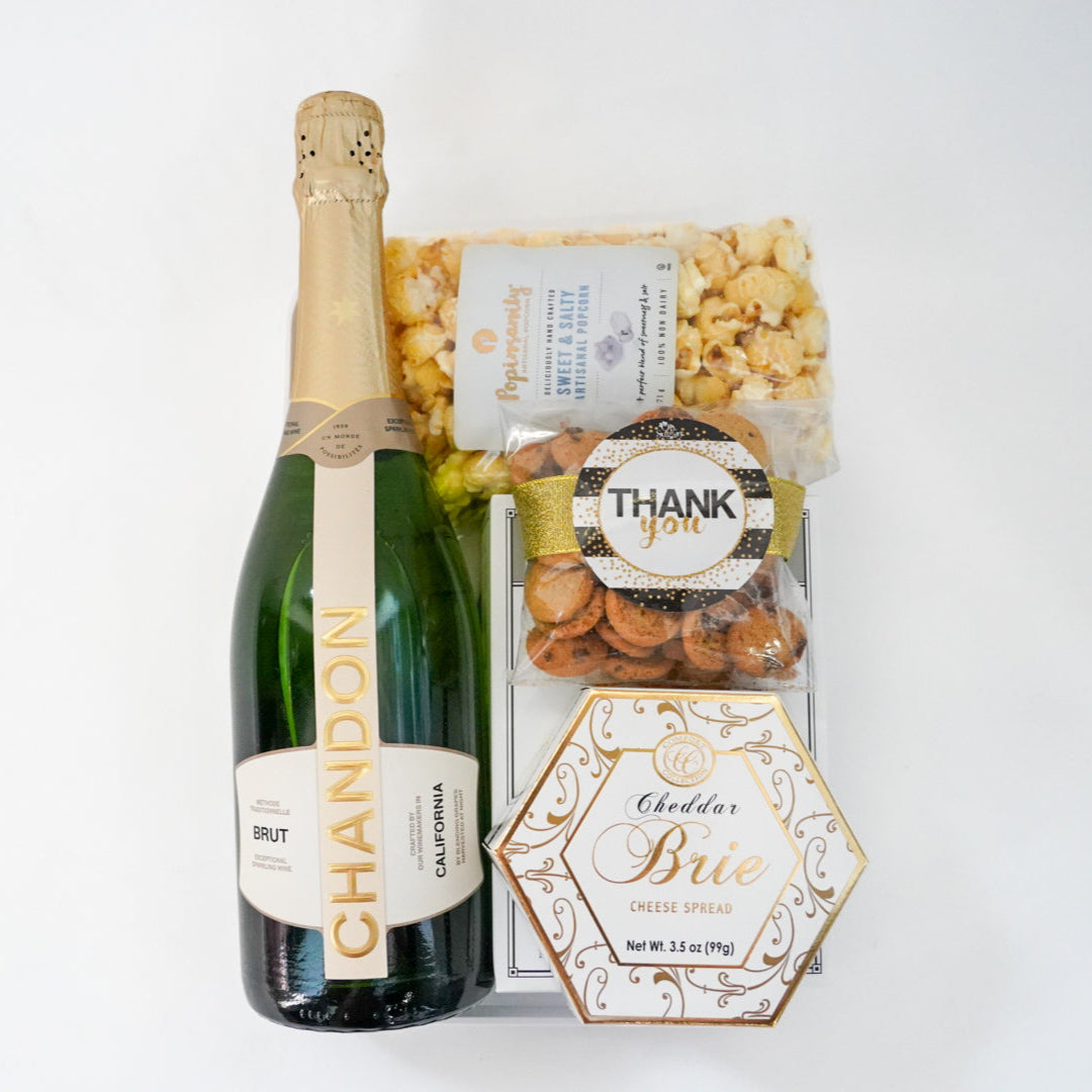 Bottle of Chandon champagne with a box of popcorn and a card on a white background