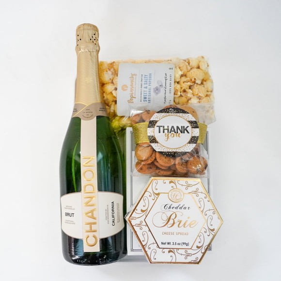 Bottle of Chandon champagne with a box of popcorn and a card on a white background