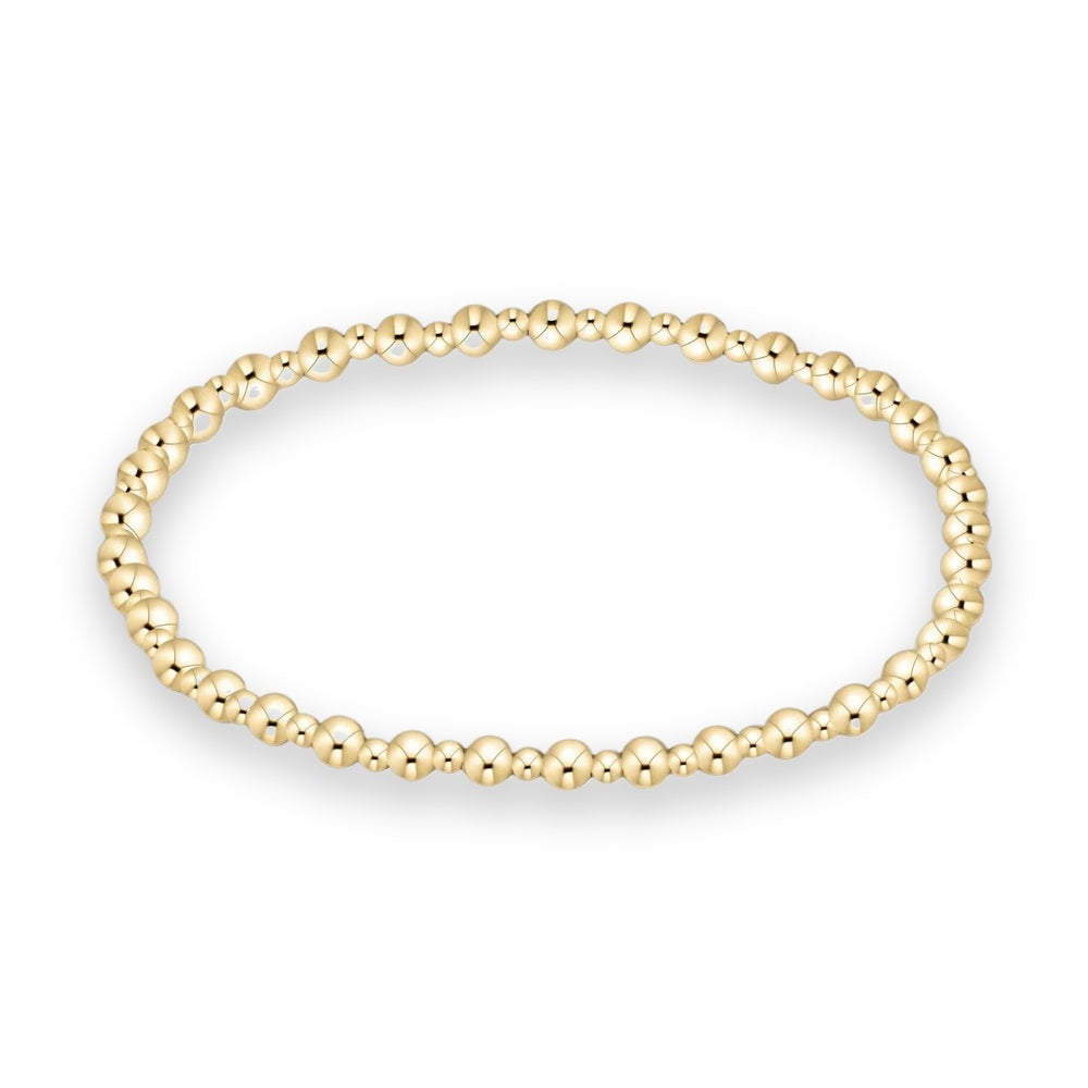 Jewelry photography of a gold beaded bracelet featuring uniform polished spherical beads with a high-shine reflective finish arranged in a continuous circular strand on a minimalist white background