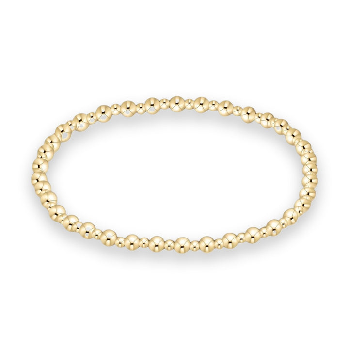 Jewelry photography of a gold beaded bracelet featuring uniform polished spherical beads with a high-shine reflective finish arranged in a continuous circular strand on a minimalist white background