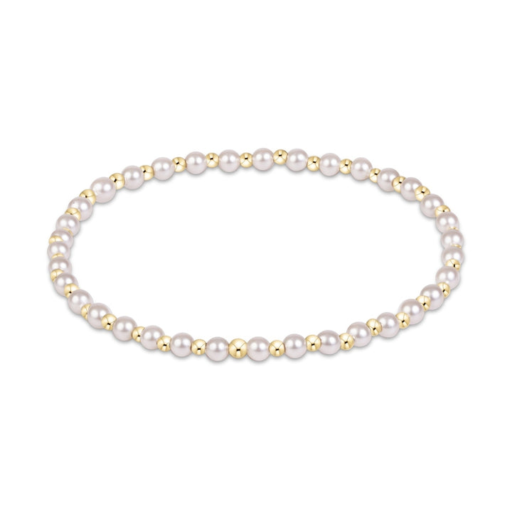 Jewelry photograph of a circular beaded bracelet on a white background featuring lustrous white pearls and small polished gold spheres in a repeating rhythmic pattern
