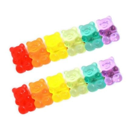 Studio photograph of multicolored gummy bear candies arranged in two parallel diagonal rows on a white background featuring translucent gelatinous textures and a vibrant rainbow spectrum of colors