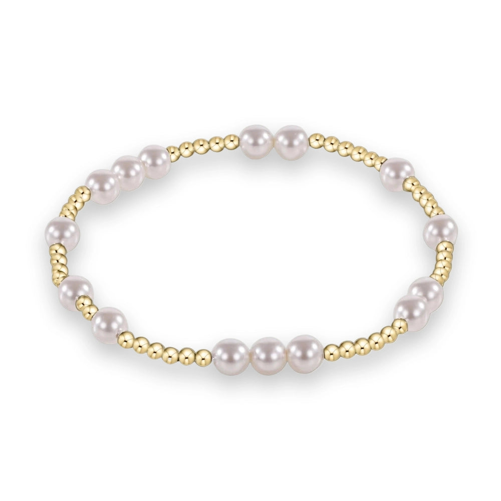 Studio photograph of a beaded bracelet featuring lustrous white pearls and polished yellow gold spherical beads in a rhythmic alternating pattern set against a solid white background