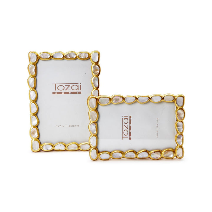 Mother-of-pearl and gold metal picture frames by Tozai Home featuring two decorative displays with iridescent shell pebbles and scalloped gilded edges on a white background