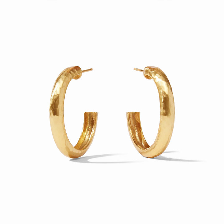 Gold-plated brass earrings featuring a pair of thick C-shaped hoops on a minimalist white background with a distinctive hammered surface and a high-shine golden luster