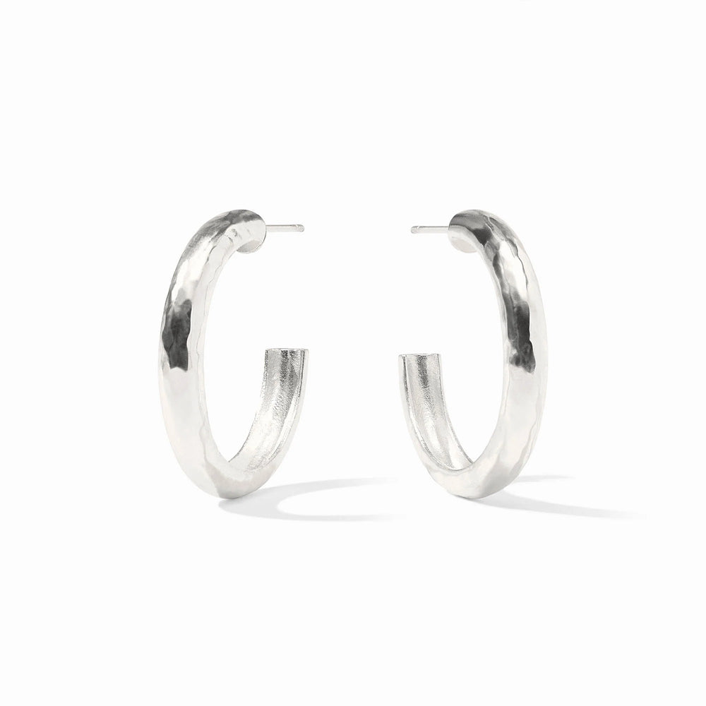 Sterling silver pair of thick hoop earrings on a white background featuring a unique hammered texture and a polished reflective finish
