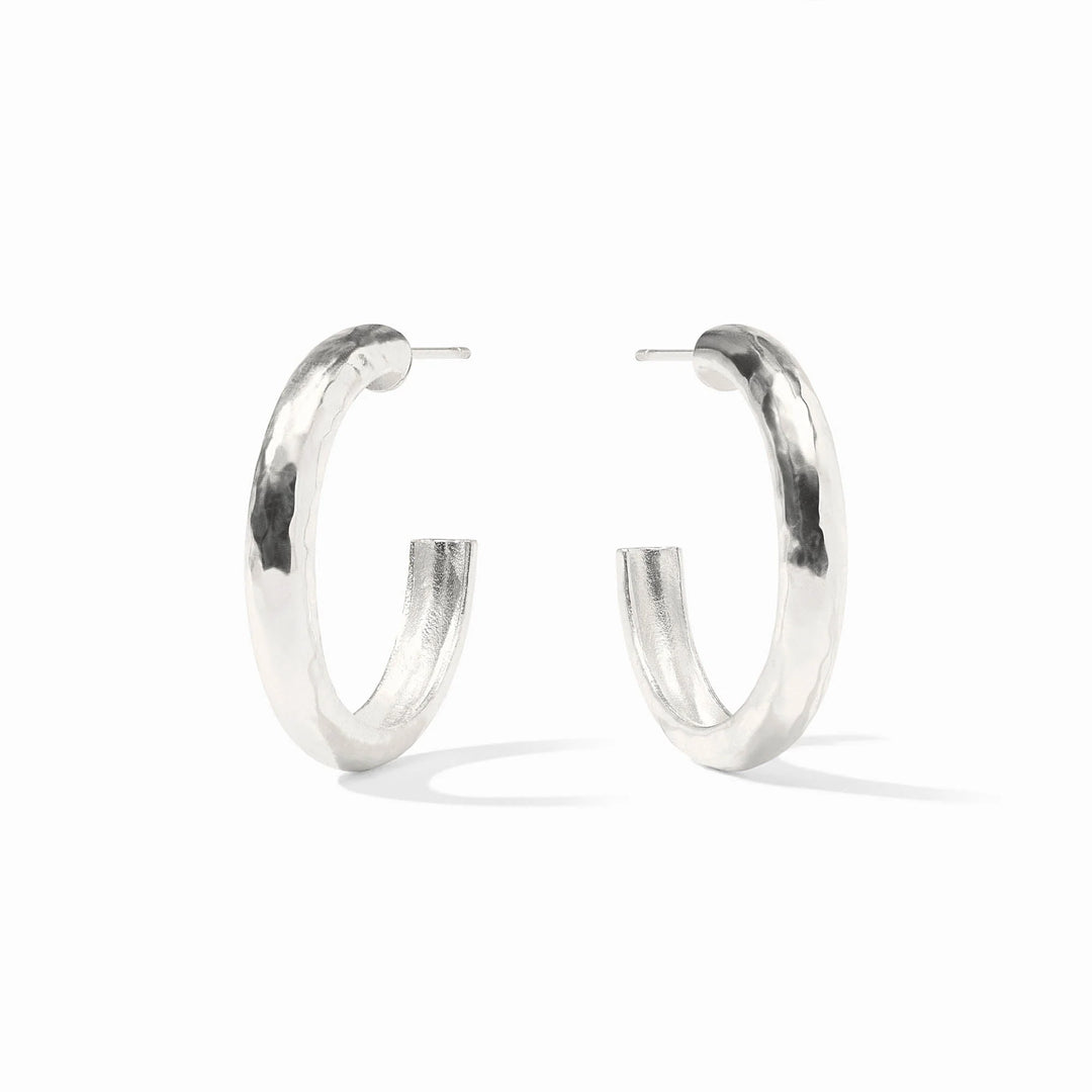 Sterling silver pair of thick hoop earrings on a white background featuring a unique hammered texture and a polished reflective finish