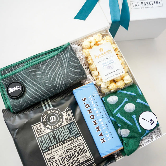 Gift box with snacks, a pouch, and a bottle labeled 'Garlic Parmesan' on a white surface.