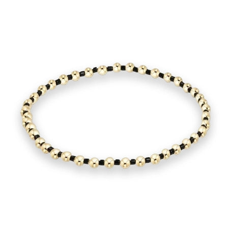 Gold and black beaded jewelry bracelet displayed on a white background featuring polished gold spheres, tiny black beads, and a symmetrical circular silhouette