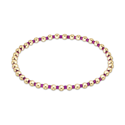 Beaded jewelry bracelet featuring alternating polished gold spherical beads and vibrant translucent purple spacer beads positioned centrally on a minimalist white background