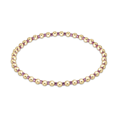 Handcrafted beaded bracelet featuring high-shine gold spherical beads and small purple translucent spacers in a repeating pattern against a clean white background
