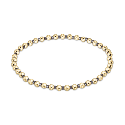 Photograph of a beaded jewelry piece featuring a circular bracelet composed of alternating polished yellow gold spheres and dark metallic spacers against a minimalist white background