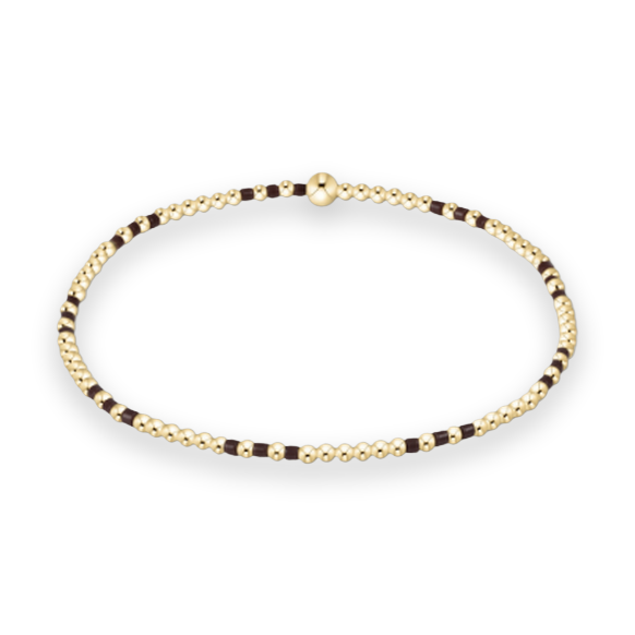 Gold-filled beaded bracelet by a jewelry designer featuring a circular design on a white background with a large central gold bead and an alternating pattern of small gold spheres and dark brown spacer beads
