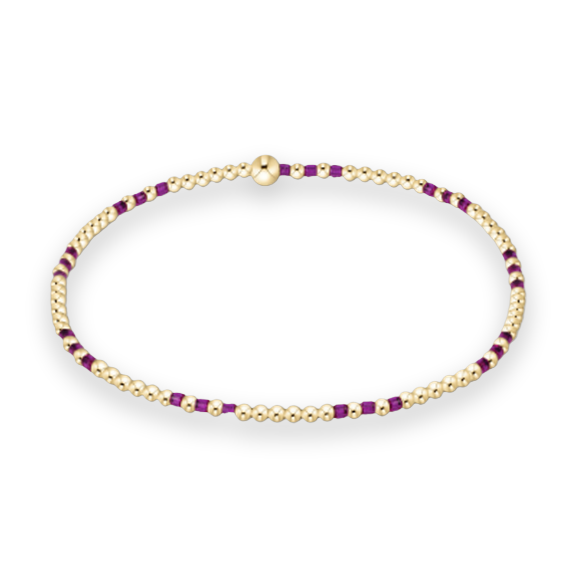 Handcrafted beaded jewelry featuring a delicate gold and purple bracelet centered on a white background with polished yellow gold spheres, vibrant violet accents, and a single larger central gold bead
