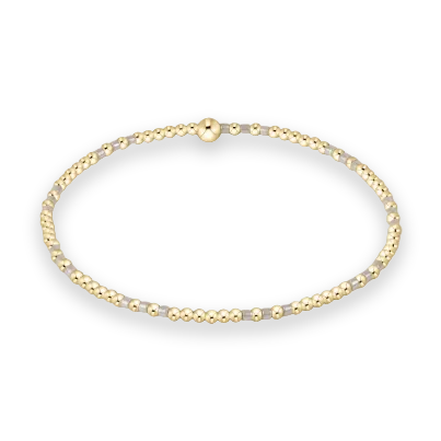 Jewelry design of a delicate beaded bracelet centered on a white studio background featuring alternating small gold spheres and gray translucent beads with a single larger polished gold bead at the top