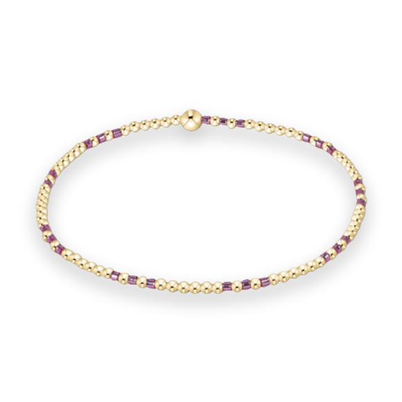 Beaded jewelry by enewton showcasing a 14kt gold-filled bracelet on a white background featuring rhythmic patterns of vibrant purple seed beads and a central large signature gold ball