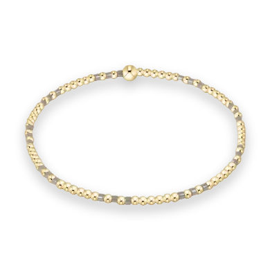 Jewelry beaded bracelet featuring tiny polished gold spheres and small translucent grey accents on a minimalist white background with a prominent larger gold bead focal point