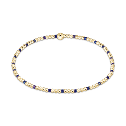 14kt gold-filled beaded bracelet by enewton featuring polished round gold spheres and dark navy blue square accents with a signature gold logo bead centered on a minimalist white background