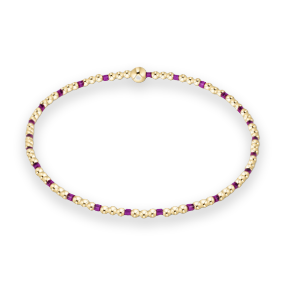 Gold and purple beaded bracelet centered on a white background featuring a sequence of small polished gold spheres, vibrant violet square-cut accents, and a prominent central gold orb
